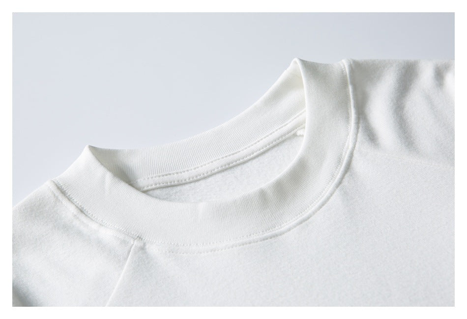 Close-up of a white sweatshirt's ribbed crew neckline and shoulder seam.