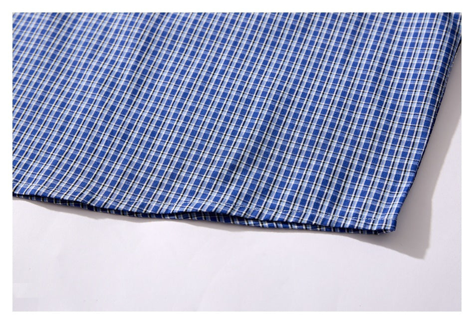 Close-up of the hem of a blue checked shirt laid flat on a white background.