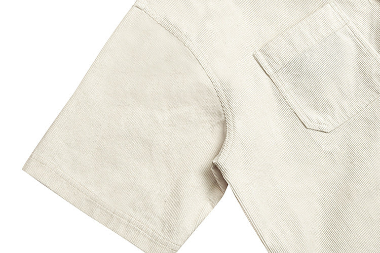 Close-up of a cream ribbed short-sleeve shirt showing the sleeve seam and chest pocket.