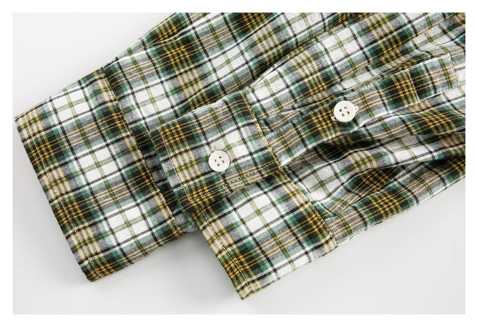 Close-up of a plaid shirt cuff with two white buttons and matching stitching.