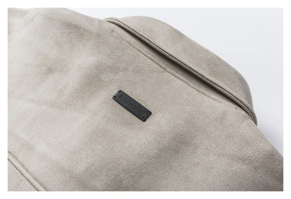 Close-up of a taupe jacket shoulder seam and small black fabric label.