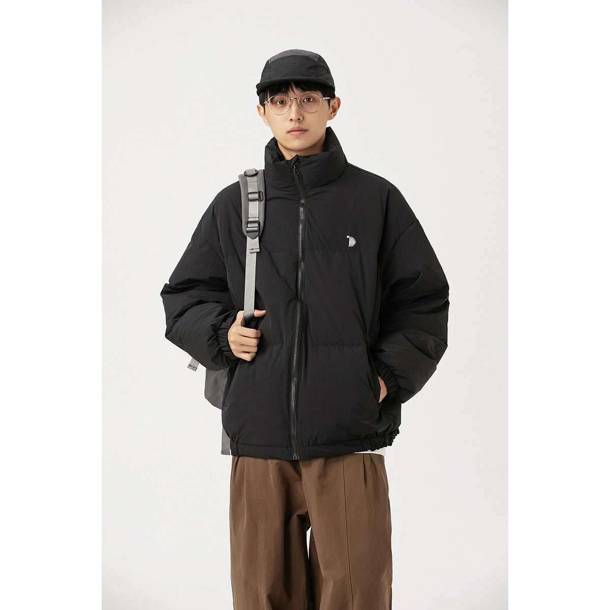 Model wearing a black high-collar puffer jacket with a front zipper and elastic cuffs.