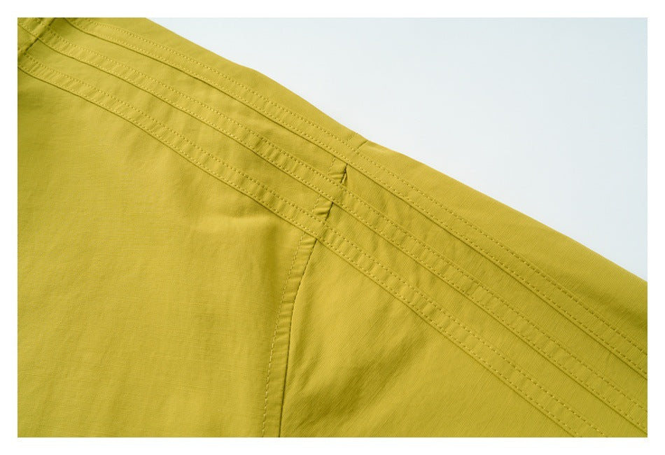 Close-up of parallel stitched seams on a mustard-yellow garment.