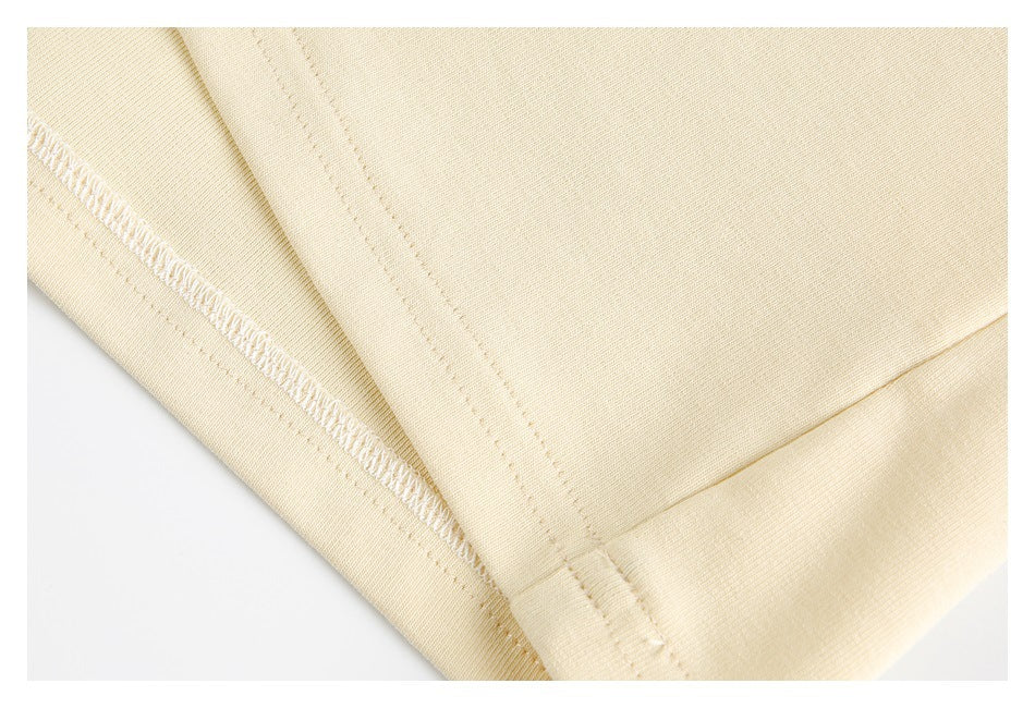Close-up of the cream garment's folded hem and interior overlock stitching.