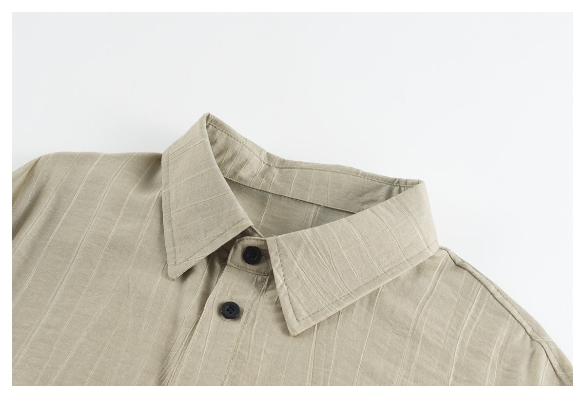 Close-up of a beige button-up shirt collar and upper placket with dark buttons and subtle vertical texture.