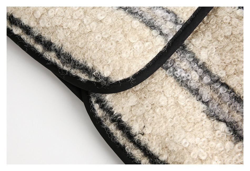 Close-up of a rounded patch pocket with black edging on a cream and gray striped fuzzy jacket.