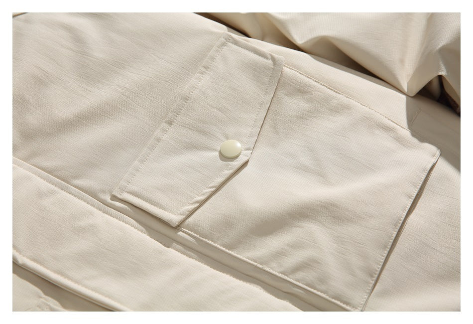 Close-up of a large flap pocket with a snap button on the ivory jacket.