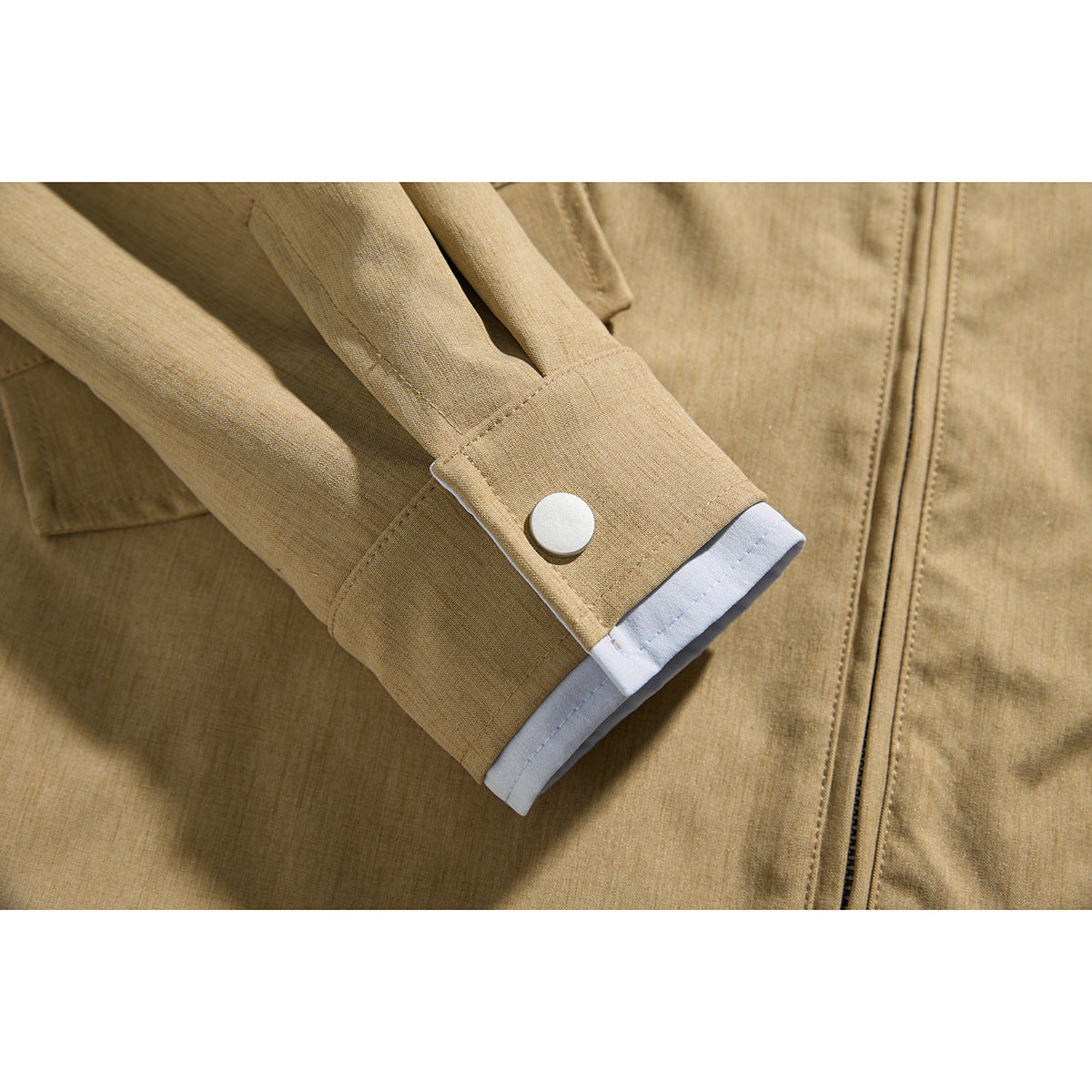 Close-up of a tan jacket's snap-button cuff with pale blue lining.