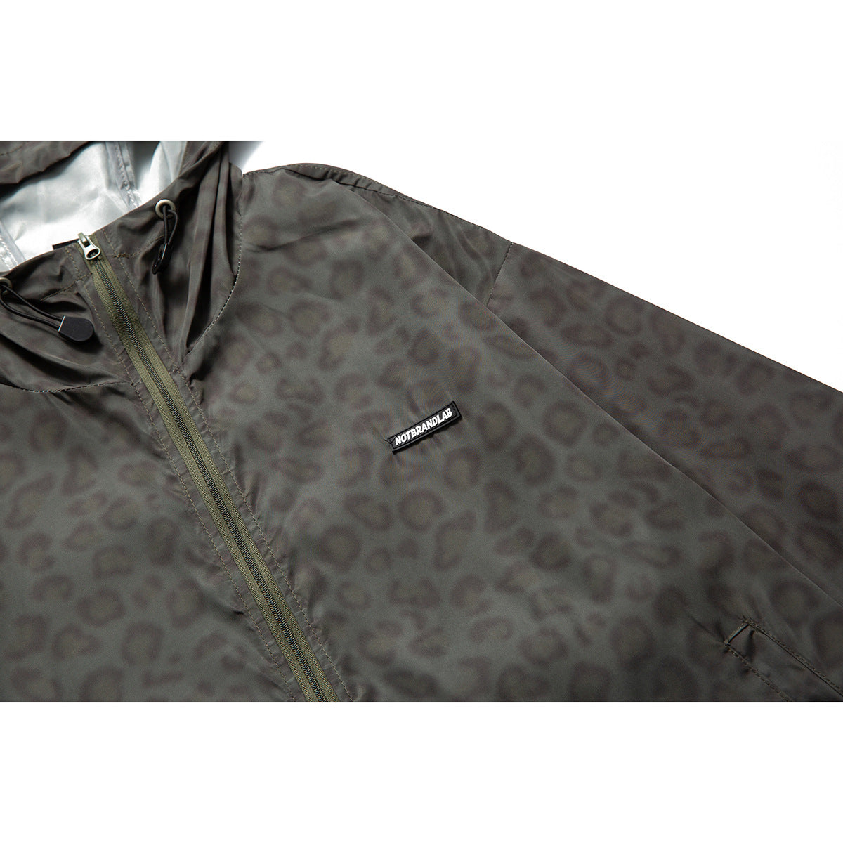 Close-up of a charcoal gray hooded jacket with a muted animal pattern, front zipper, drawcords, and a small chest label.