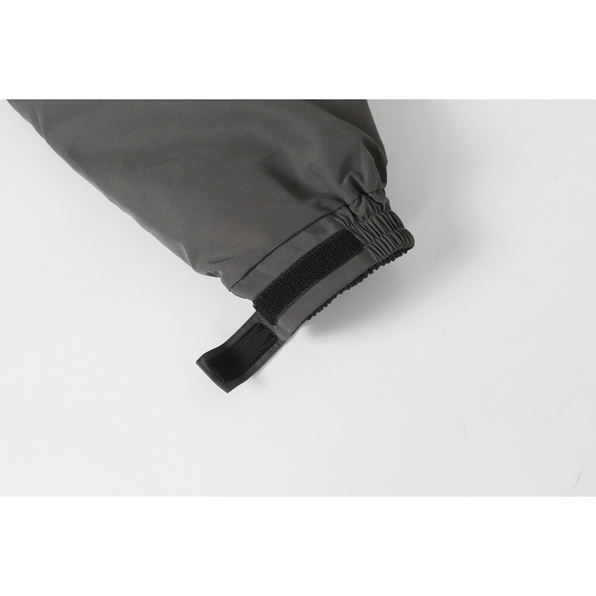 Close-up of a charcoal jacket sleeve cuff with elastic gathering and an adjustable black hook-and-loop tab.