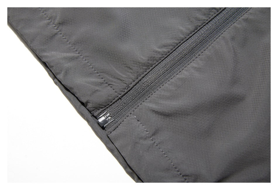 Close-up of a dark gray garment showing a diagonal zipper and stitched panel seams.