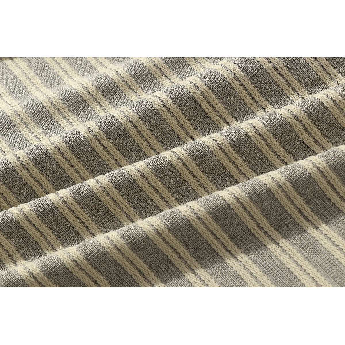 Close-up of textured gray and cream striped fabric arranged in soft folds.
