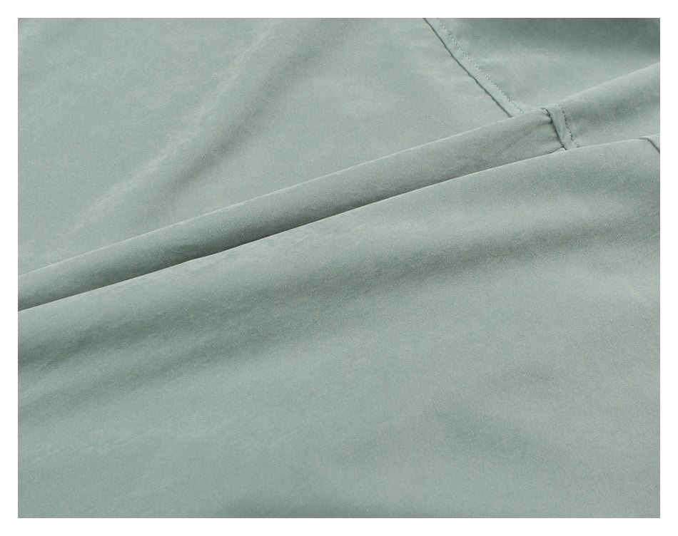 Close-up of sage green garment fabric with a diagonal seam and folded edge.