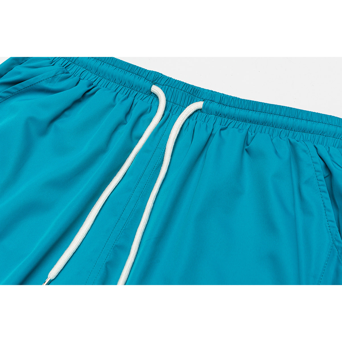 Close-up of turquoise shorts with an elastic waistband, white drawstrings, and stitched front seams.