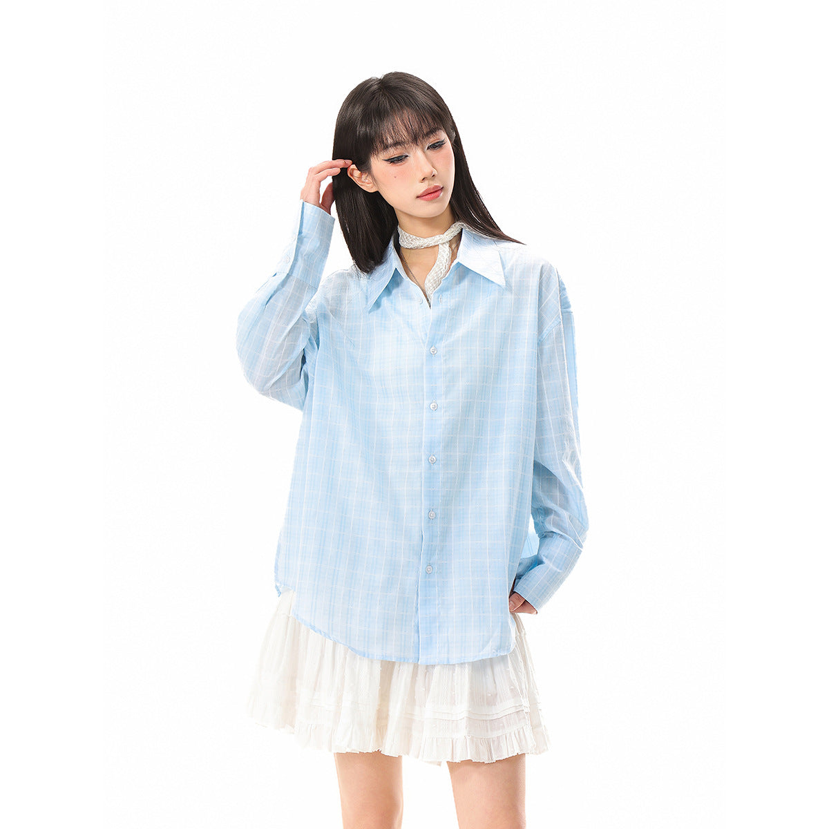 Model wearing an oversized light blue windowpane-check button-up shirt with a white ruffled skirt.