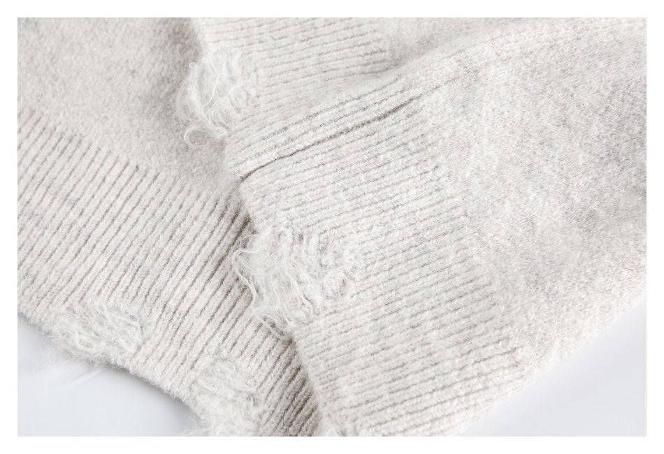 Close-up of an ivory fuzzy knit sweater showing a ribbed edge and seams.