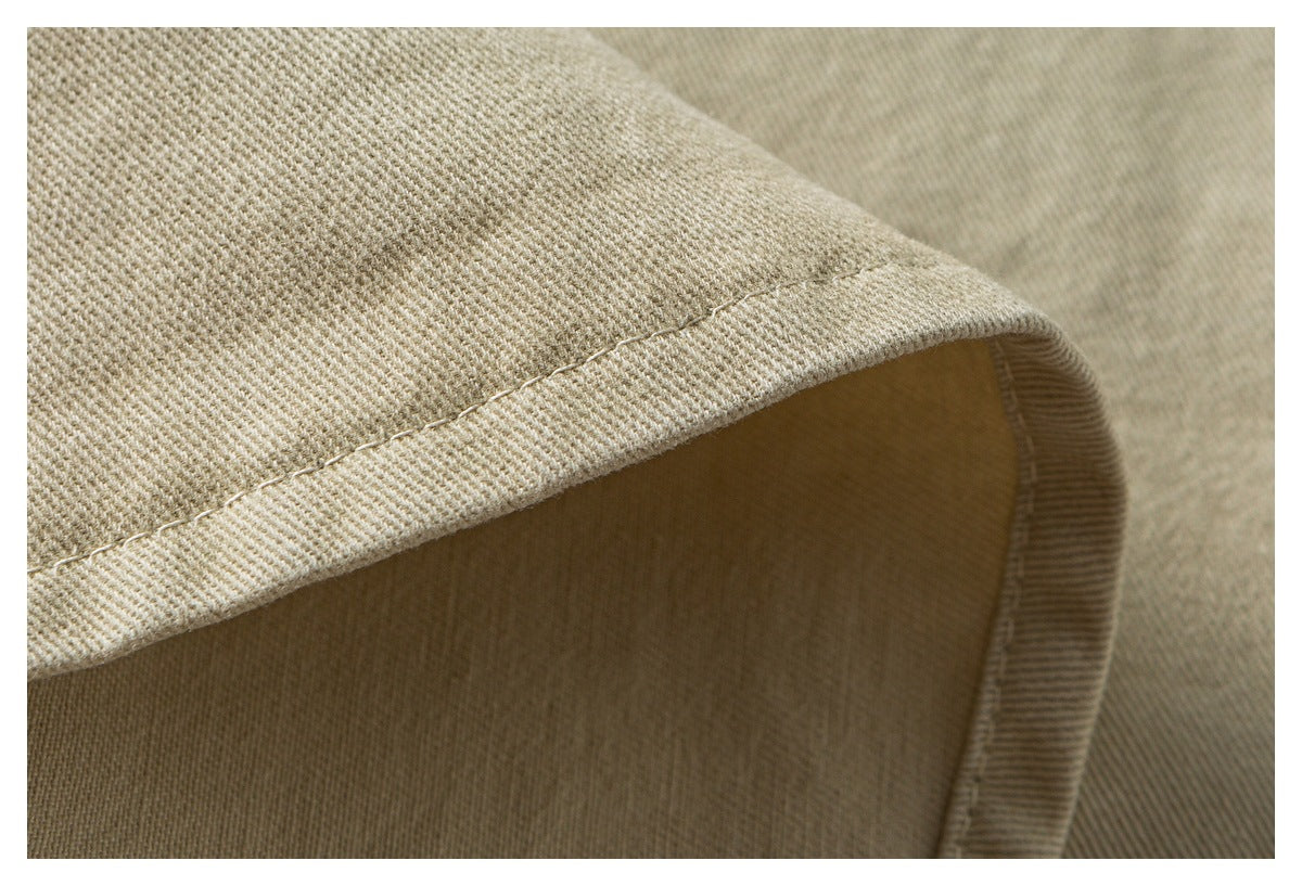 Close-up of beige fabric hem with visible stitching and a curved folded edge.