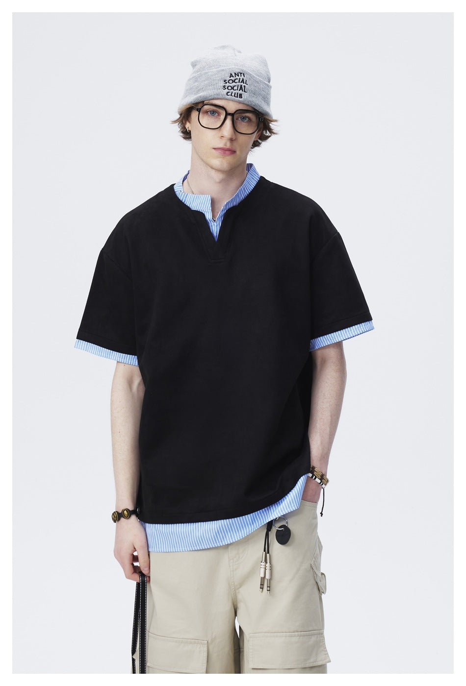 Closer view of a model wearing an oversized black V-neck tee over a blue-and-white striped shirt.
