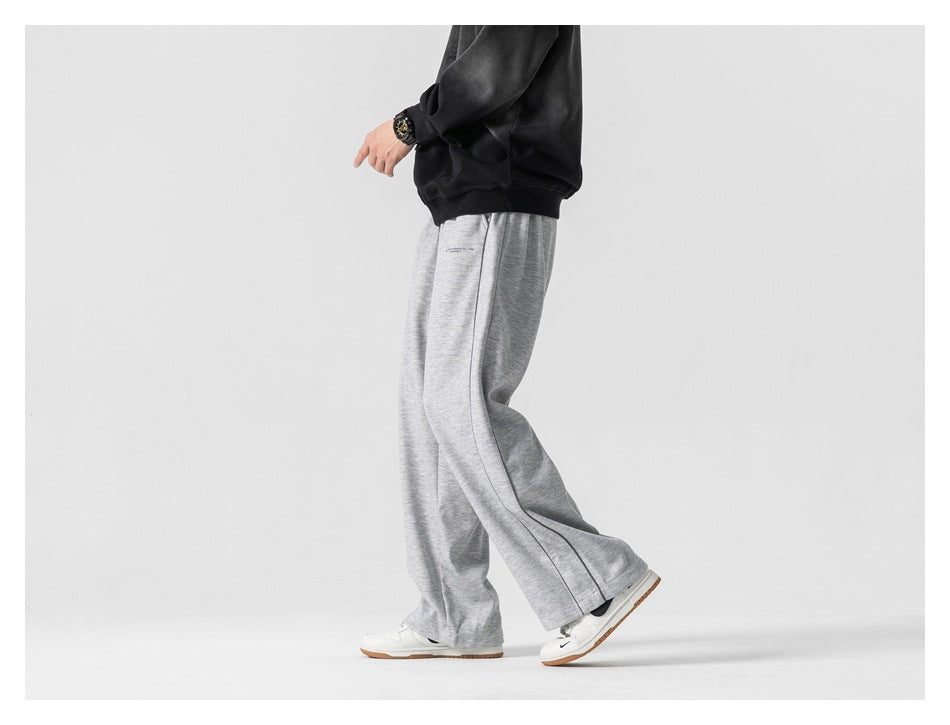 Side view of a model wearing light gray wide-leg pants with dark piping.