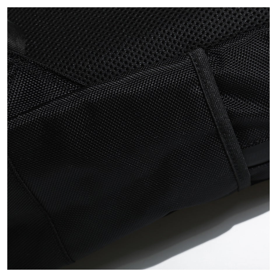 Close-up of a black backpack showing textured fabric, mesh padding, and a vertical webbing strap.