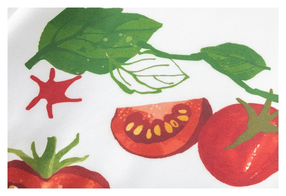 Close-up of a white garment's tomato-and-leaf print in red, orange and green.