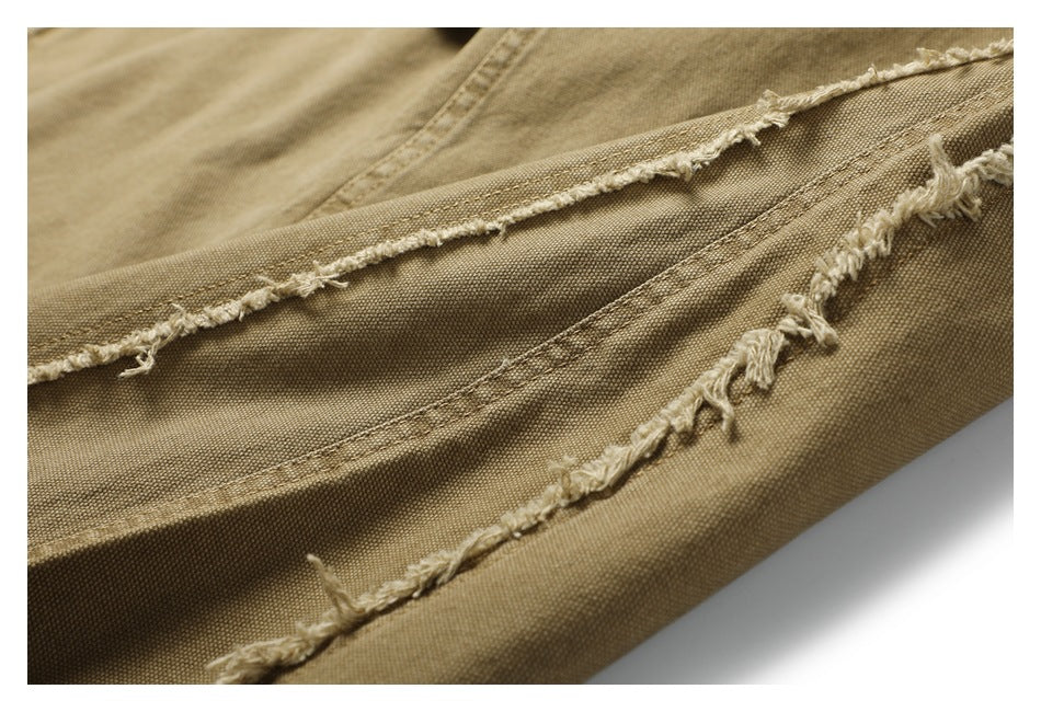 Close-up of tan trousers showing frayed, raw-edge seams and visible woven texture.