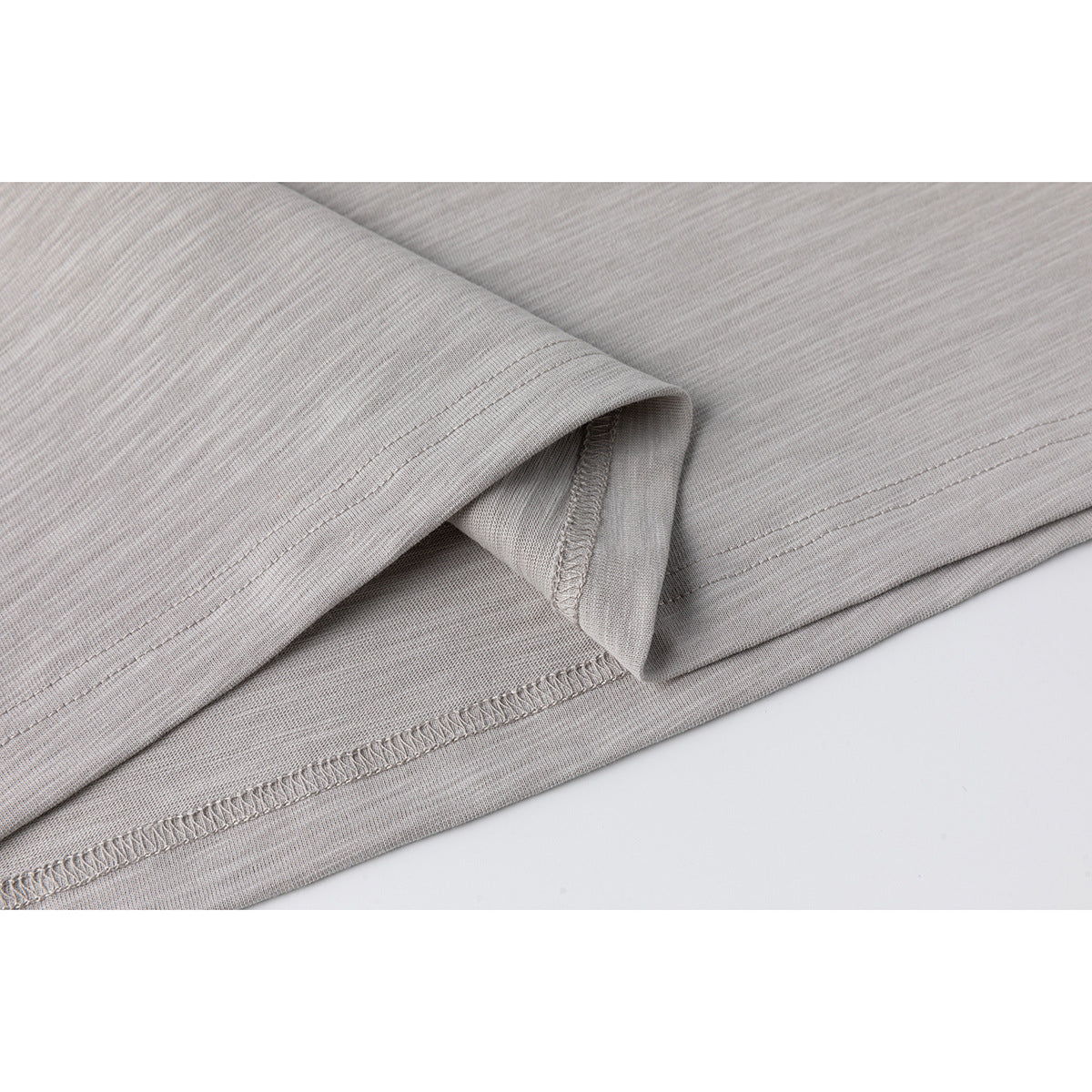 Close-up of a light gray heather shirt showing the folded sleeve edge and stitched hem.