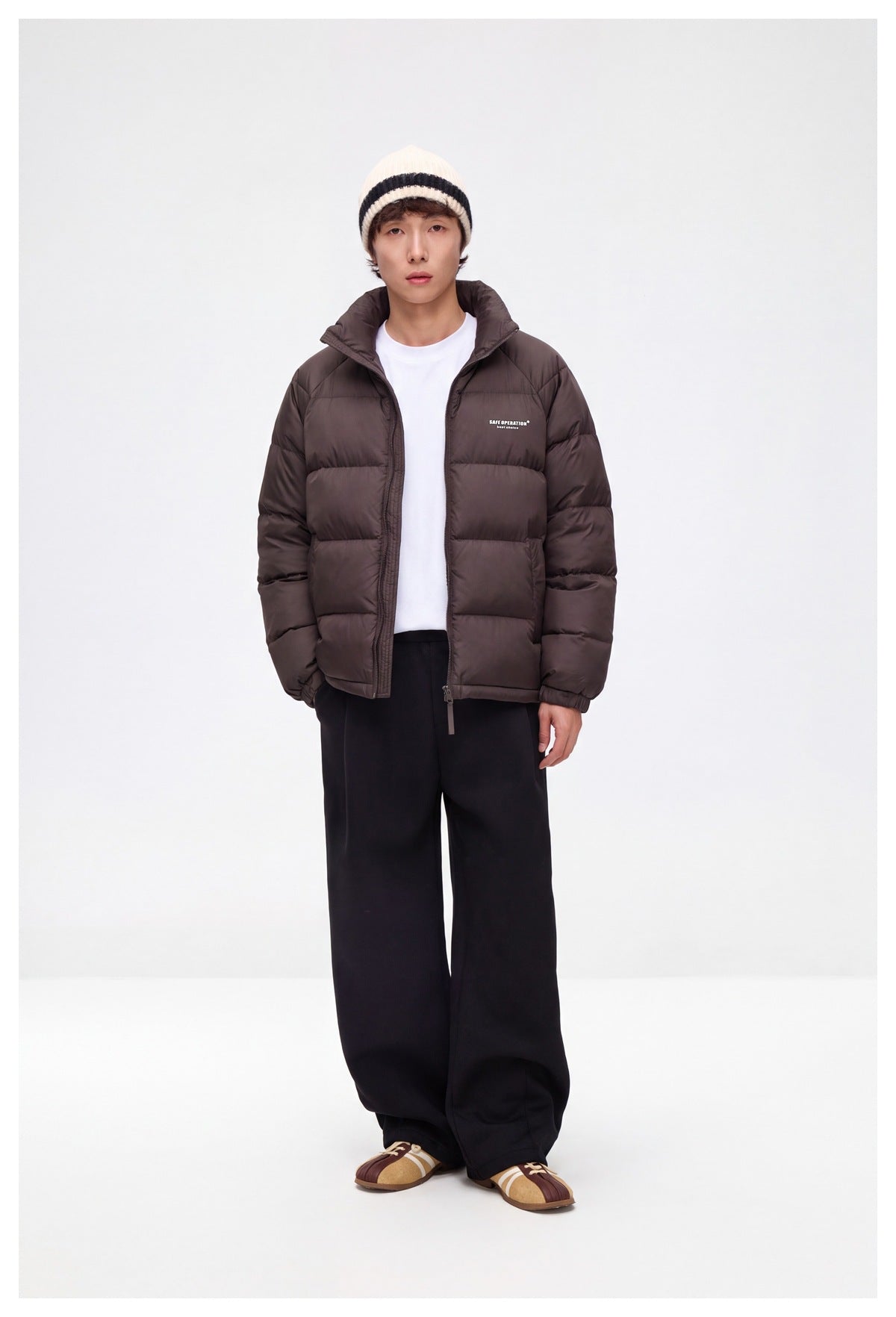 Full-length view of a model wearing a dark brown quilted puffer jacket with a high collar and zip front.