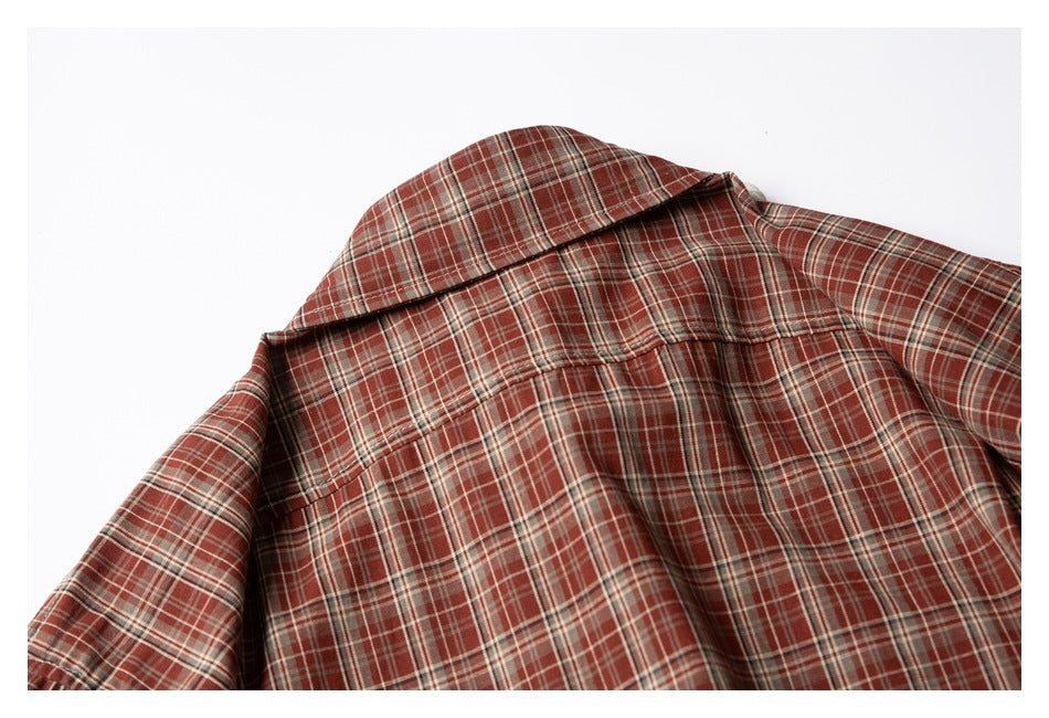 Close-up of the shirt back showing its pointed collar and yoke seam in rust-red plaid.