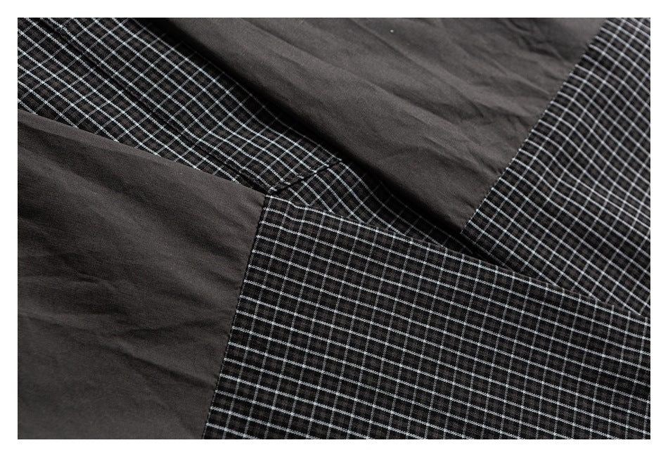 Close-up of black checked fabric panels joined beside plain dark fabric.