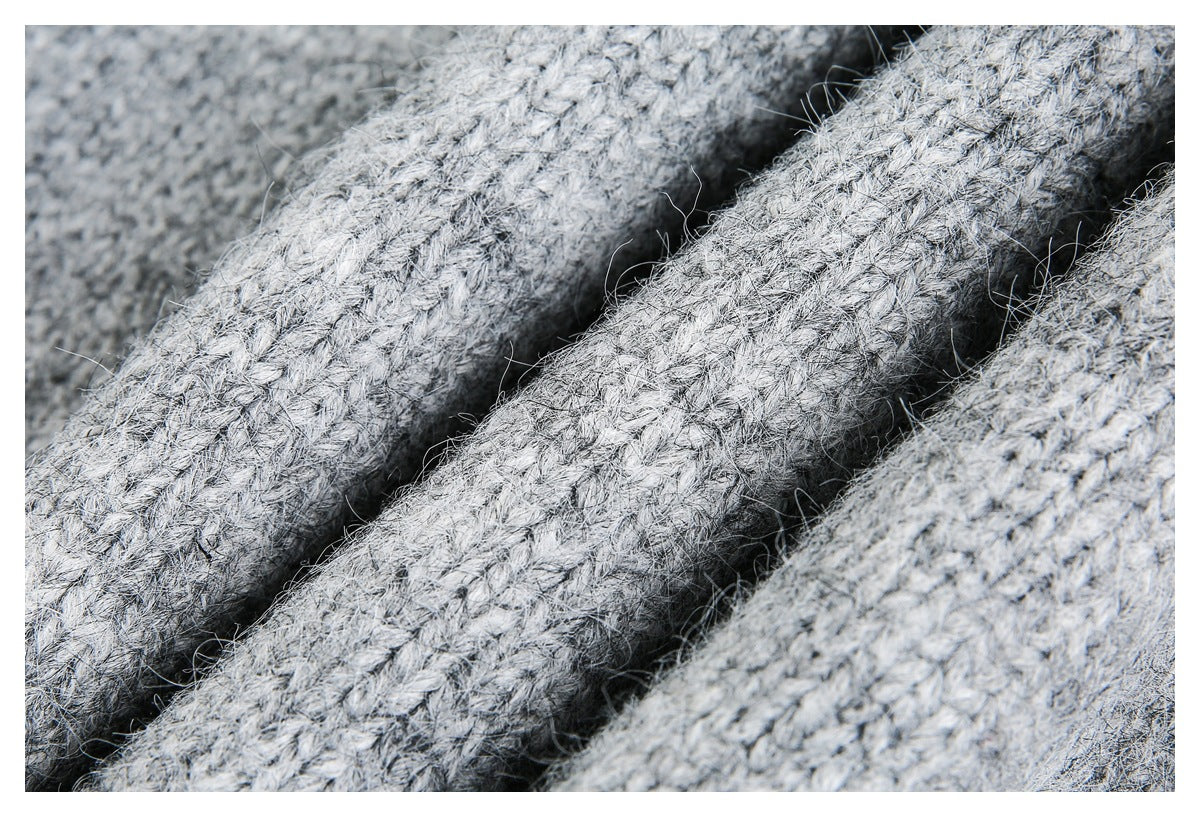 Extreme close-up of chunky light gray knit stitches and loose fibers.