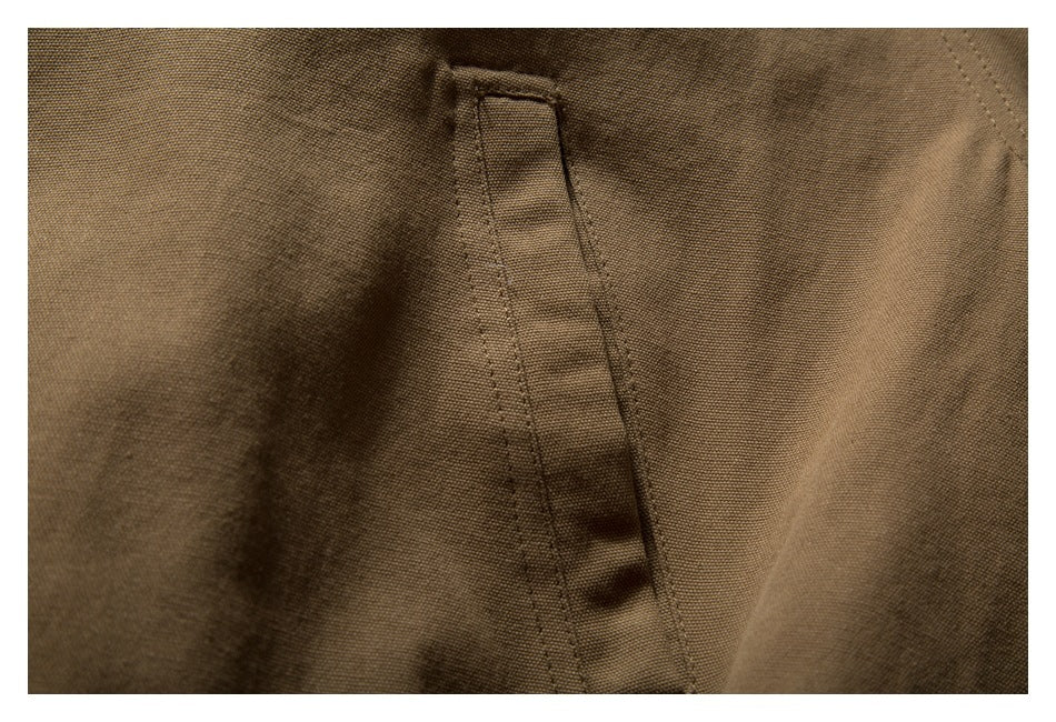 Close-up of a vertical welt pocket on brown jacket fabric.