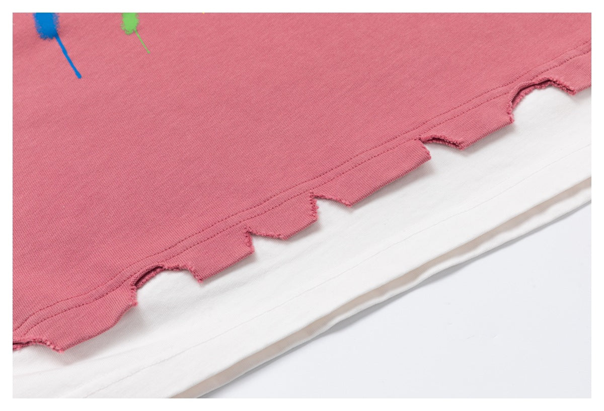 Close-up of a dusty rose sweatshirt hem with an irregular cut edge layered over a white garment.