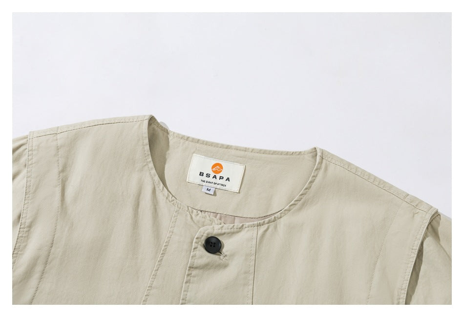 Close-up of a pale beige garment neckline with a black button and sewn-in brand and size labels.