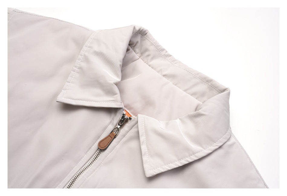 Close-up of a pale gray jacket collar and silver front zipper with a brown pull tab.