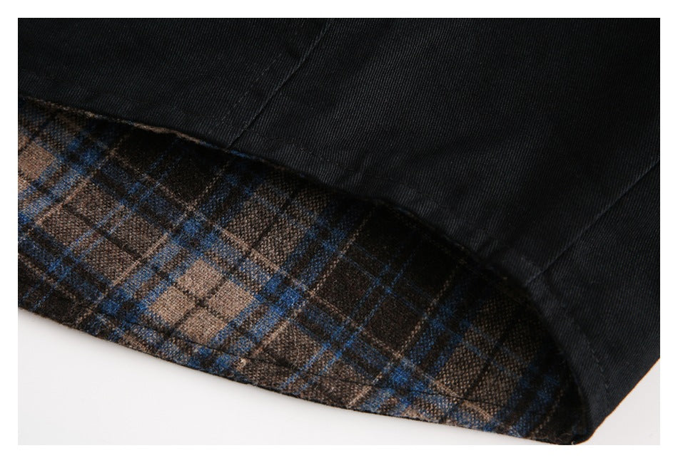 Close-up of the black jacket hem with brown and blue plaid lining visible beneath.