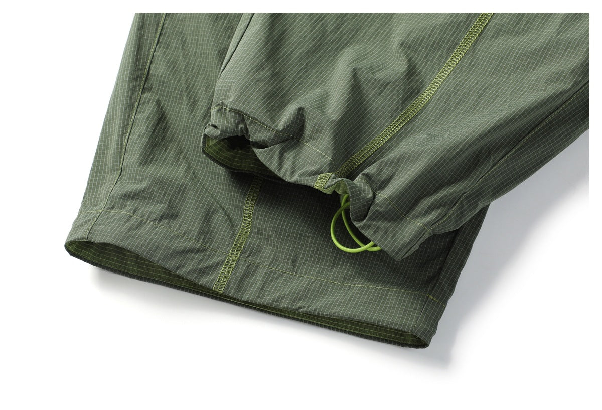 Close-up of an olive-green grid-patterned garment hem with a lime drawcord loop and stitched seams.