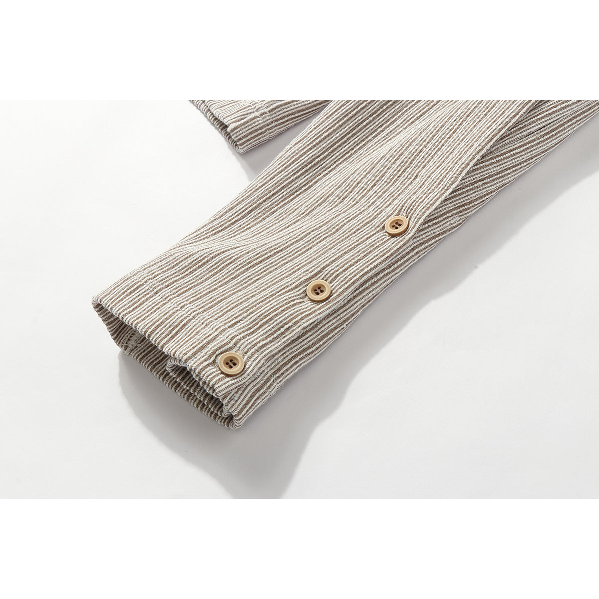 Close-up of a striped sleeve cuff with three tan buttons.