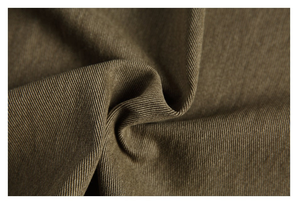 Macro view of olive-brown fabric gathered to show its fine diagonal weave.