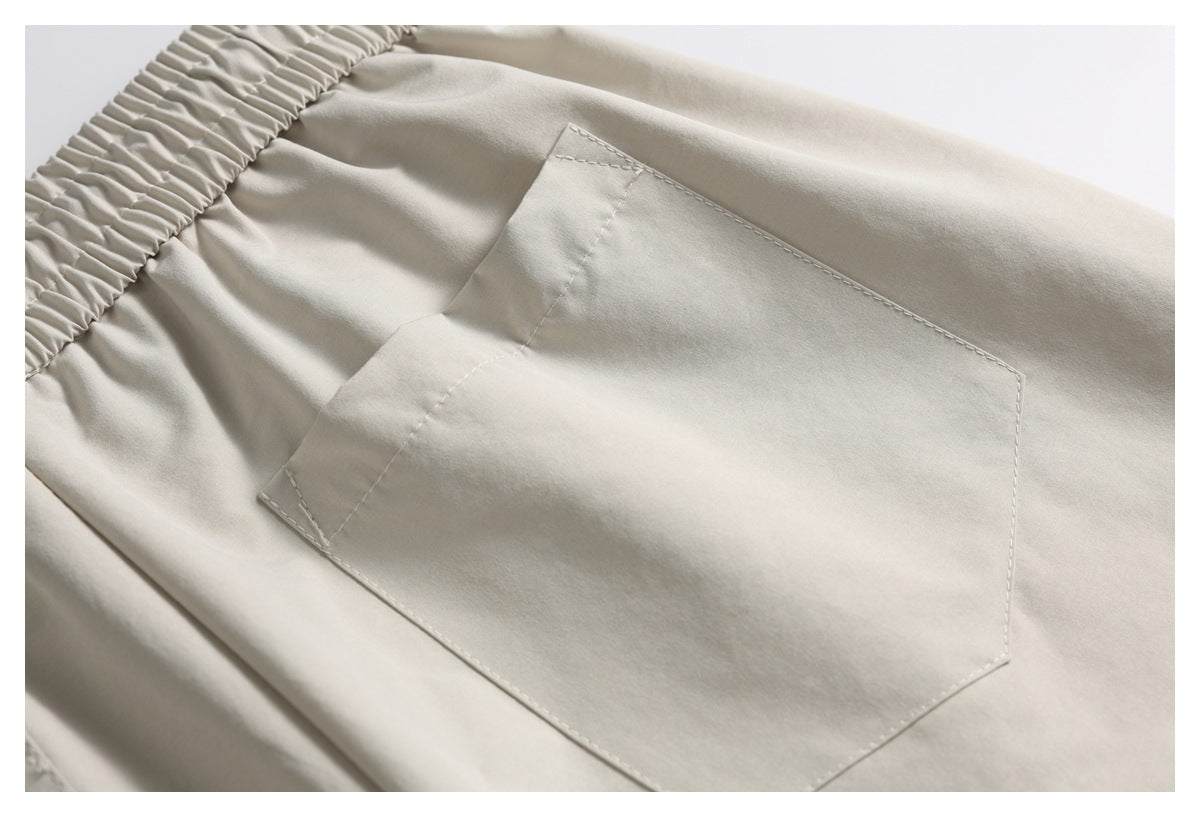 Close-up of a large stitched rear patch pocket on light beige shorts.