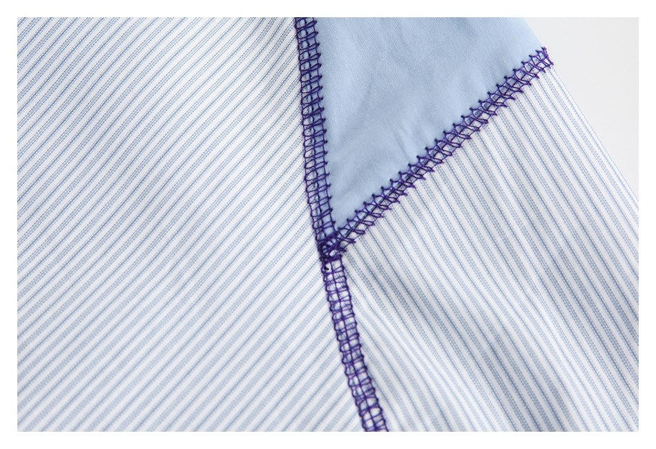 Close-up of purple overlock seams at the junction of striped fabric and a pale blue panel.