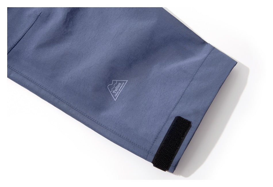 Blue jacket sleeve cuff with a black hook-and-loop tab and a small outlined logo.