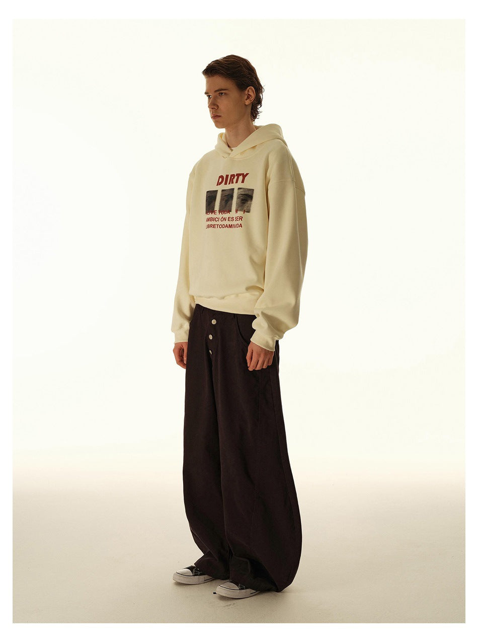 Model in side profile wearing a cream graphic hoodie and wide black trousers.