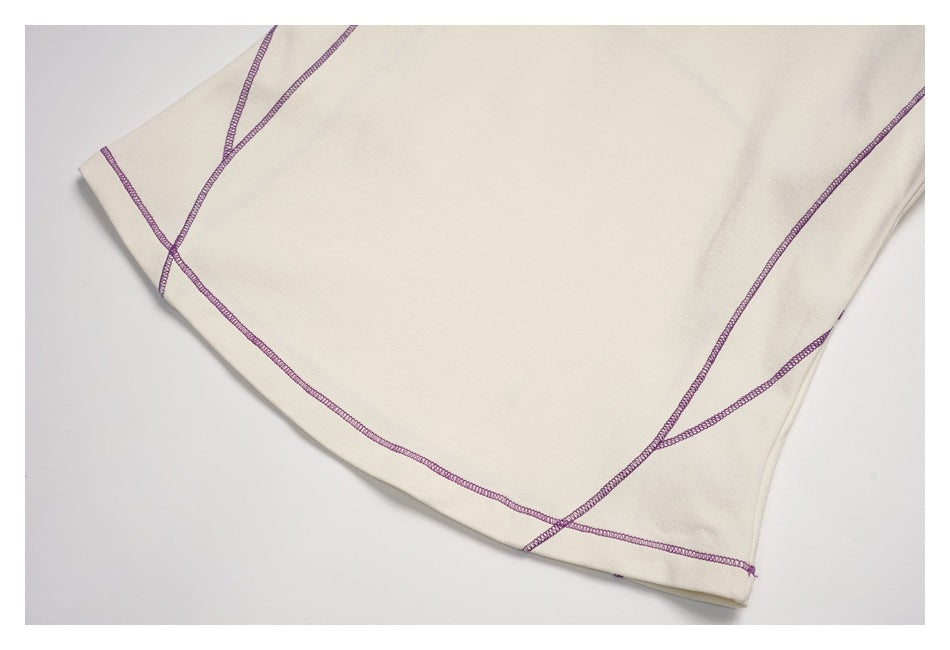 Close-up of an ivory garment with intersecting purple overlock seams.