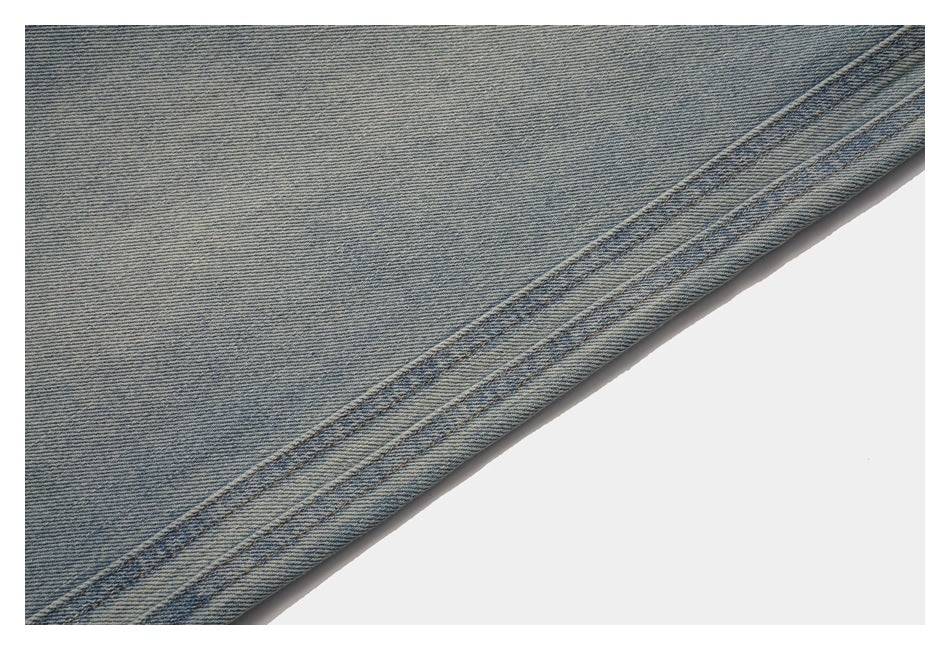 Close-up of the double-stitched hem on a faded blue denim jeans leg.