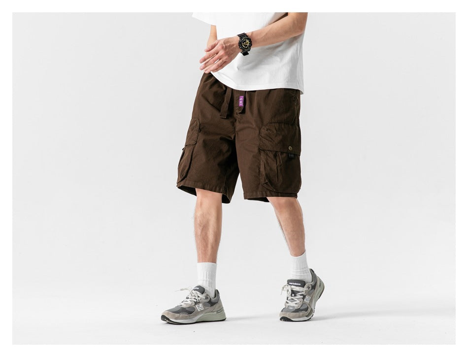Angled view of a model wearing dark brown cargo shorts with large flap pockets and a drawstring waist.