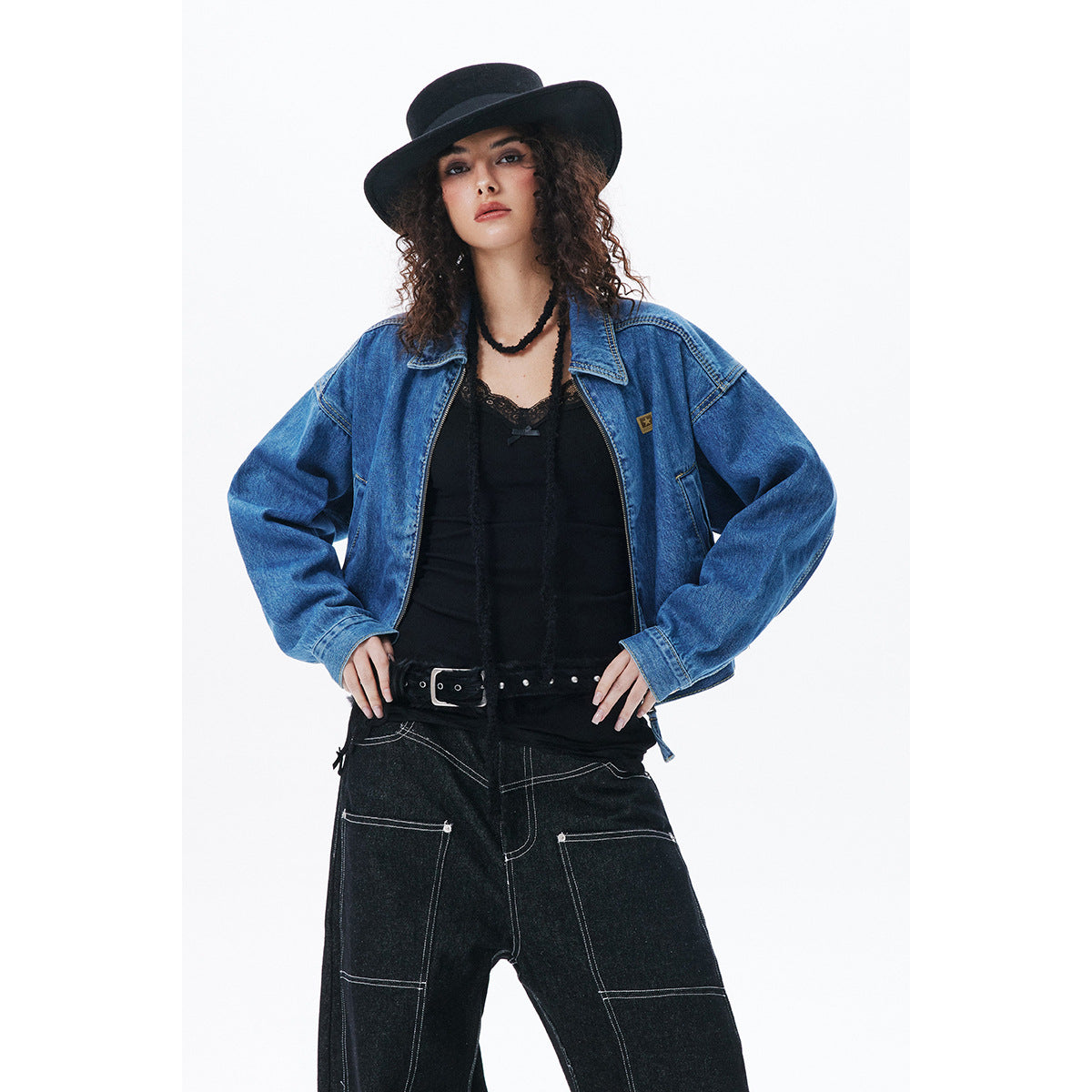 Model wearing an oversized blue denim zip jacket with black wide-leg jeans and a black hat, shown from the front.