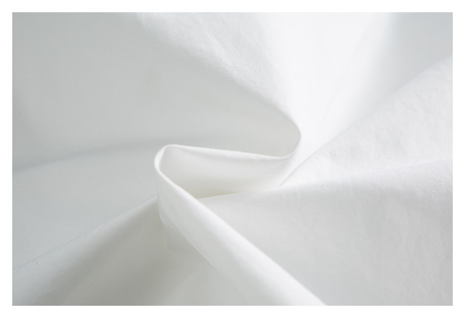 Close-up showing the smooth white fabric of a garment folded into soft layers.