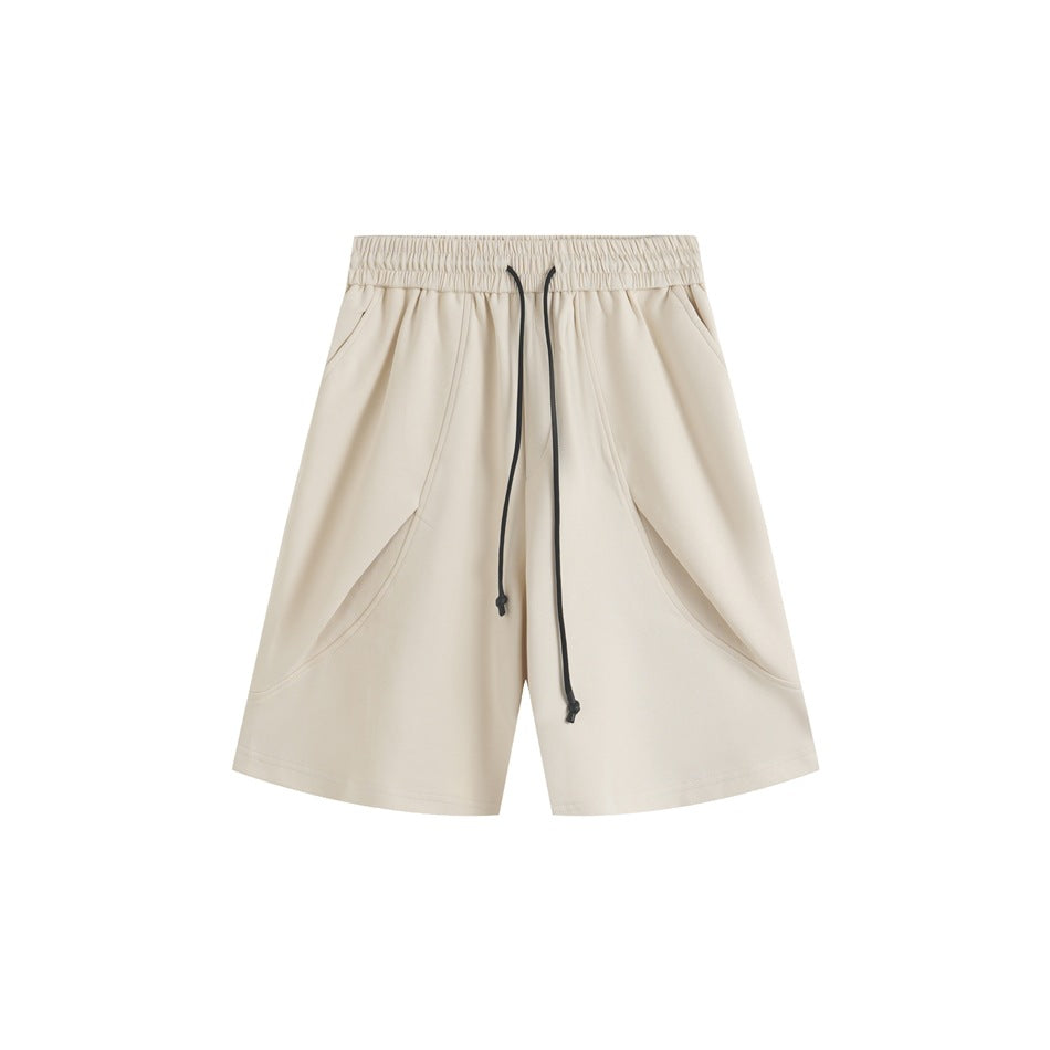 Beige knee-length shorts with black drawstring, elastic waist, curved front seams and side pockets, flat lay front view