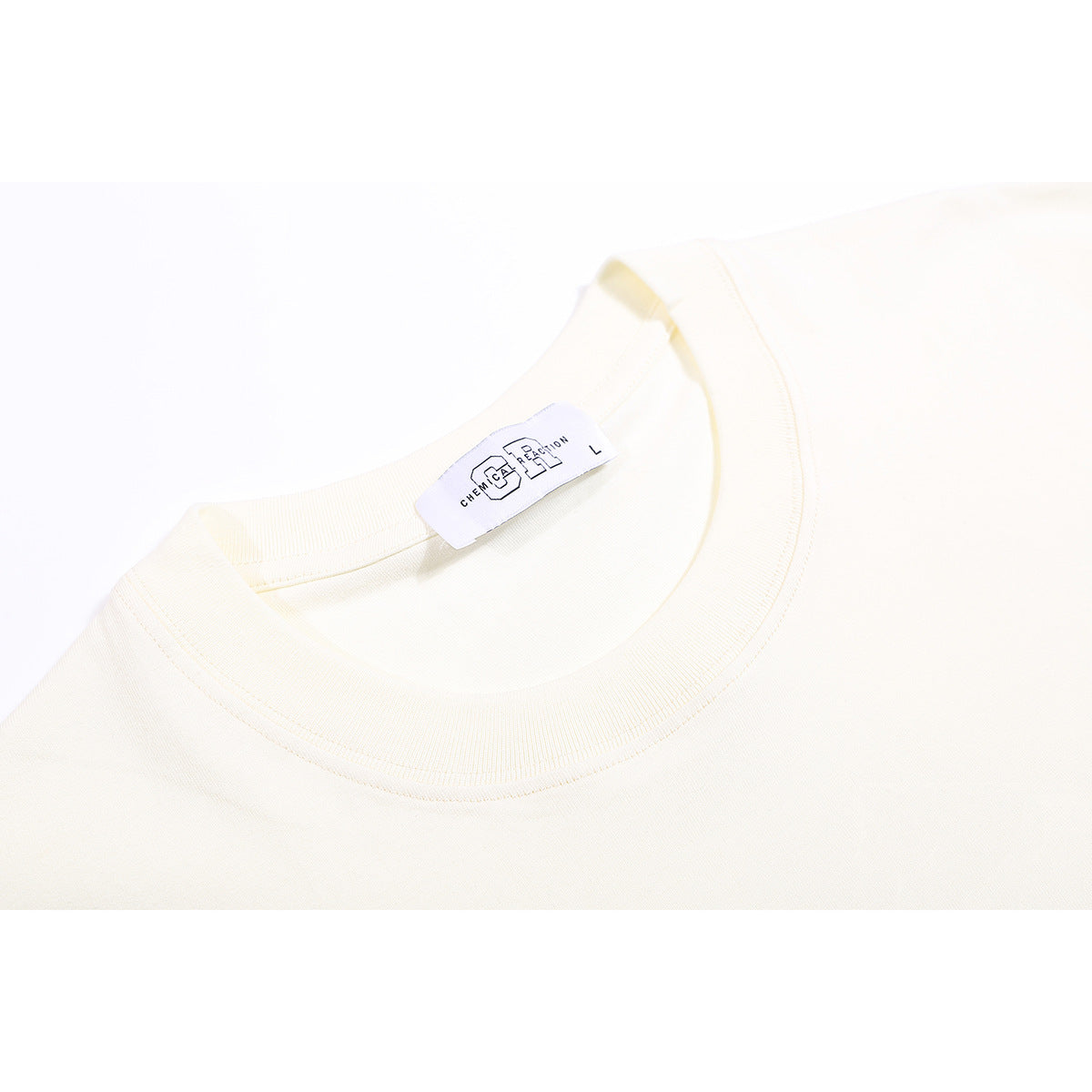 Close-up of an ivory T-shirt's ribbed crew neckline and sewn-in neck label.
